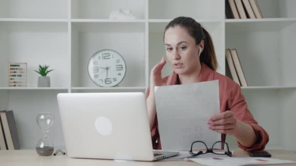 Joven mujer de negocios con auriculares comunicándose por videollamada. Mujer hablando mirando a la computadora portátil, conferencia en línea distancia oficina chat, virtual training concept.Errors en el — Vídeo de stock