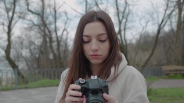 Mutlu esmer kadın güzel bir parkta, boş zamanlarında ve ön manzarada fotoğraf çekiyor.