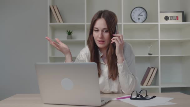Mujer de negocios hablando por teléfono mientras usa el ordenador portátil — Vídeo de stock