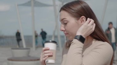 Kulaklıkla müzik dinleyen çekici genç bir kadın. Şehirde akıllı telefon kullanıyor. Etrafına bak.