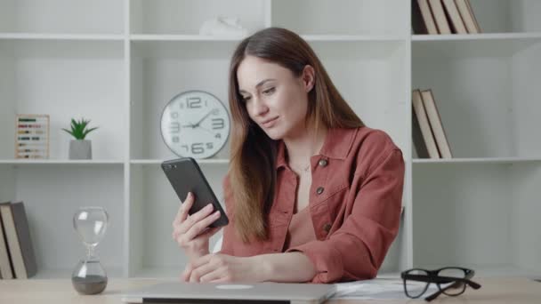 Close-up portret van jonge vrouw met koptelefoon luisteren naar muziek op airpods en glimlachen op kantoor — Stockvideo