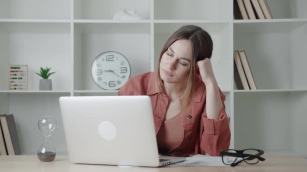 Uma jovem cansada está trabalhando usando seu computador portátil. Mulher sonolenta adormece no local de trabalho. — Vídeo de Stock