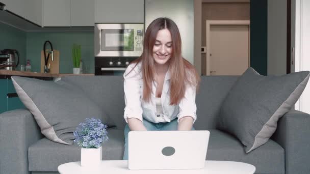 Podekscytowana młoda kobieta zwycięzca patrzy na laptopa świętuje sukces online siedzi na kanapie w domu. Euforia pani dostaje nowe możliwości pracy na odległość, czyta dobre wieści w e-mailu, cieszy zwycięstwo, czuje się zmotywowany. — Wideo stockowe