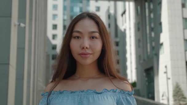 Sorrindo Asiático jovem mulher em com ombros nus roupa olhando para câmera fora na rua se sentir feliz milenial retrato bonito fêmea bonita moderna senhora muito lento movimento — Vídeo de Stock