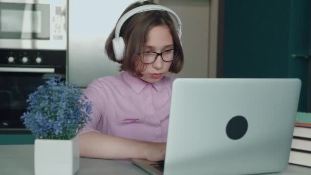 Η ιδέα της εξ αποστάσεως εκπαίδευσης. Εφηβική μαθήτρια που σπουδάζει online χρησιμοποιώντας σημειώσεις για λάπτοπ. Έφηβη μαθήτρια που φοράει ακουστικά και παρακολουθεί μαθήματα βίντεο στο διαδίκτυο στο home desk. — Αρχείο Βίντεο