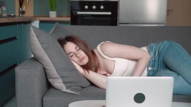 Уставшая или скучающая молодая сонная женщина падает на диван. Уставшая от работы и домашней работы молодая девушка пытается уснуть — стоковое видео