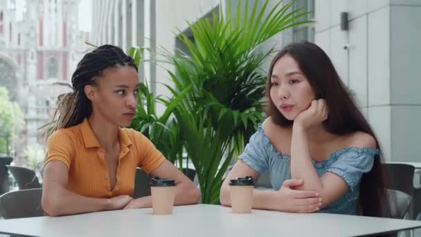 Dos mujeres jóvenes hablando y tomando café sentadas en la cafetería. — Vídeo de stock