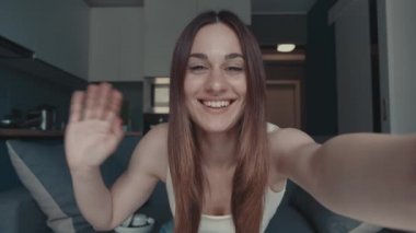 Neşeli genç kadın kameraya bakıyor, gülüyor, mutlu kadın blogcu web kamerasına konuşuyor, video konferans görüşmesi yapıyor, çöpçatan sohbeti yapıyor ya da blog blogu kaydediyor kanepeye oturuyor, web kamera görüntüsü