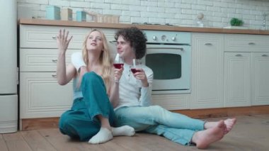 Genç ve mutlu çiftler sıcak zeminde oturuyorlar. Şarapla kadeh tokuşturmak, tatili kutlamak, kiralık dairelerde romantik bir randevu.