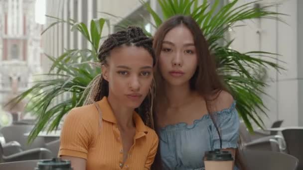 Attrayant mixte race fille et asiatique femelle étreinte montrant l'amour et l'affection regarder caméra en plein air assis à caffe sourire heureux frends ensemble mignon joli adolescent portrait gros plan — Video