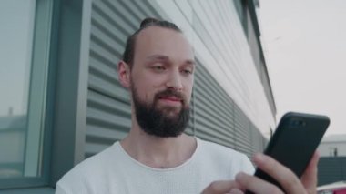 Erkek milenyum hipster 'ı modern akıllı telefon mesajları tutuyor. Genç işadamı, iş zamanı yönetim organizasyonu için park geçmişi üzerine yararlı mobil uygulamalar kullanıyor.
