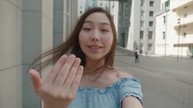 Güzel Asyalı kadın dışarıda akıllı telefon kullanarak görüntülü konuşma yapıyor. Seyahat maceralarını paylaşıyor. Şehirli arkadaşları ve sosyal medya tatili için selfie videosu çeken kızı gösteriyor.