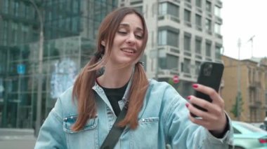 Güzel bir kadın dışarıda akıllı telefon kullanarak görüntülü konuşma yapıyor. Seyahat maceralarını paylaşıyor. Şehirli arkadaşlar ve sosyal medya tatili için selfie çeken kızlar.