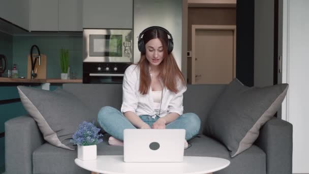 Mujer joven lleva auriculares conferencia de llamadas en las conversaciones portátiles con el profesor en línea que estudia, trabajando desde casa. Concepto de educación a distancia — Vídeo de stock