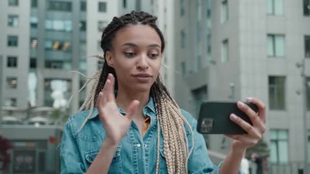 데님 재킷 블로그에 레게 머리를 하고 있거나 고층 건물 주변의 스마트폰에서 비디오 채팅을 하고 있는 아프리카 계 미국인 여성 — 비디오