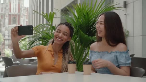 Una mujer discapacitada feliz está tomando una foto selfie con su amiga mientras está sentada en la cafetería de la calle afuera. — Vídeo de stock