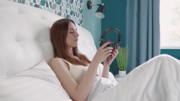 Confiant jeune femme couché écouteurs heureux écouter de la musique avec se détendre et profiter dans la chambre, plaisir féminin et se détendre casque avec la lecture de chanson sur téléphone portable intelligent, concept de style de vie. — Video