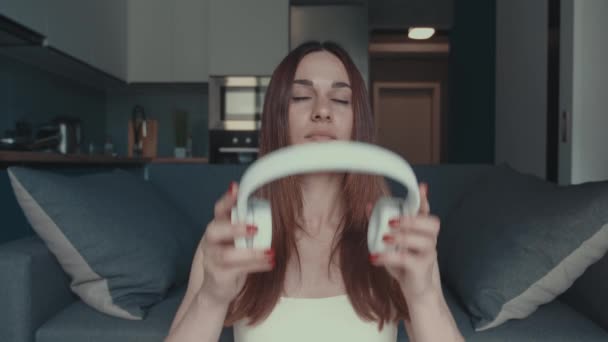 Mujer sonriente Ponerse los auriculares y escuchar música en el interior moderno — Vídeos de Stock