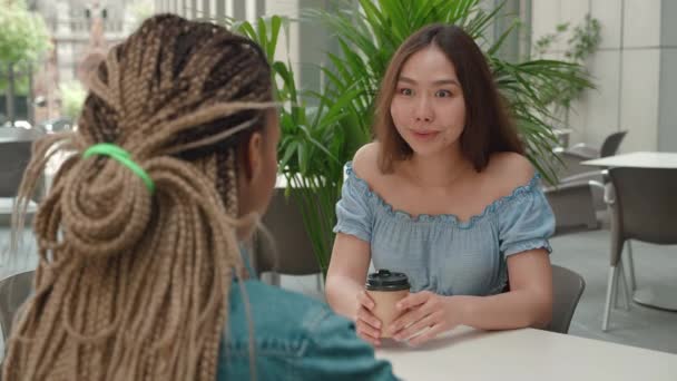 Dos amigas hablando por café fuera de una cafetería. Enfoque de mujer asiática. Sobre el hombro disparado — Vídeos de Stock