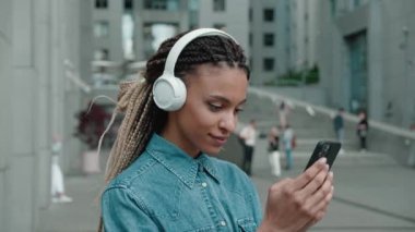 Müzik listesi dinlerken akıllı telefon ve kulaklık kullanan karışık ırk kızı - teknoloji ve moda yaşam tarzı konsepti