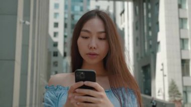 Şok olmuş genç Asyalı kadın Evet haykırır şaşkınlık içinde akıllı telefona bakar olumlu duygulardan zevk alarak ellerini bükerek.