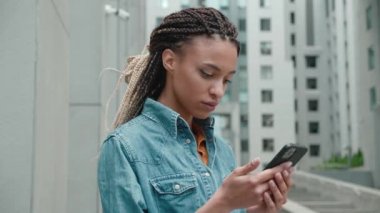 Şok olmuş Afrikalı karışık ırk öğrencisi stresli görünüyor. Akıllı telefon ekranına bakın, sorun var diye endişeleniyor. Kötü haberleri okuyun.