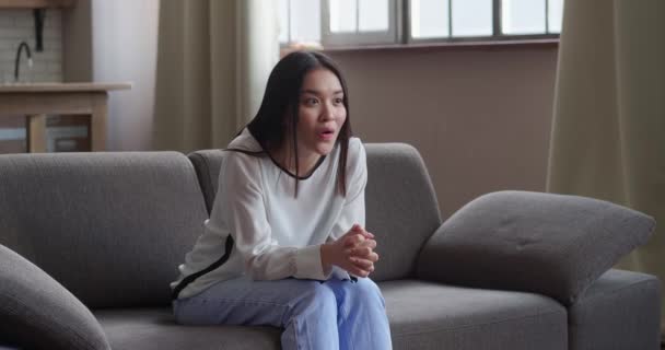 해피 아시아인젊은 여성 이 소파에 앉아 TV 시청은 온라인 로또 승리를 축하하는 것에 흥분되고, — 비디오