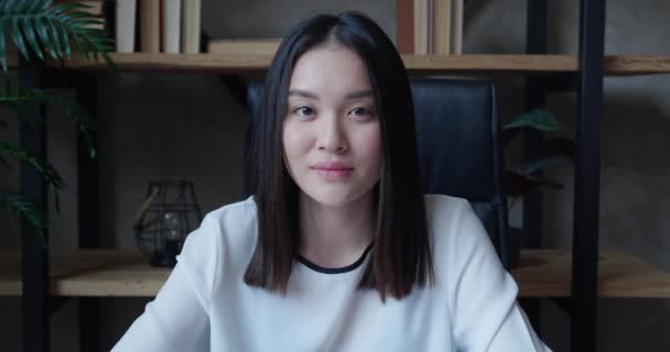 Förvånad asiatisk kvinna som tittar på kameran. Ganska kvinnligt wow uttryck. Närbild ung flicka poserar på suddig modern kontor bakgrund — Stockvideo