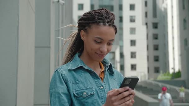 Gemengd ras meisje jas met behulp van Smart telefoon buitenshuis van het business center de achtergrond — Stockvideo