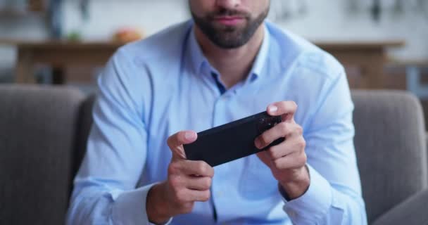 Stijlvolle volwassen onherkenbare zakenman zitten in gezellige bank en het spelen van mobiele spel. — Stockvideo