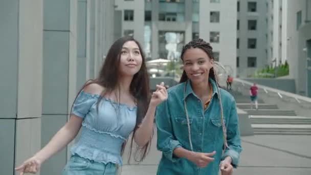 Ön manzara. İki sevimli Asyalı ve Afrikalı Amerikalı kız. Şehir sokaklarında dans edip eğleniyorlar.. — Stok video