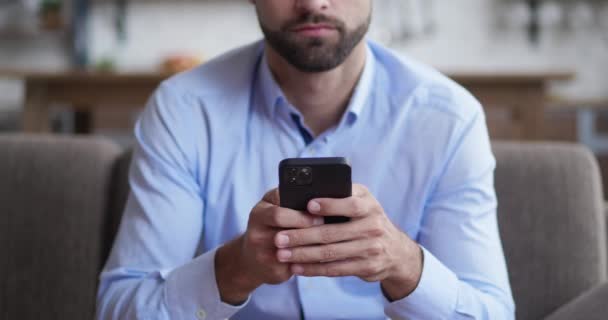 Retrato tiro do jovem alegre gravando enquanto mensagens de texto no dispositivo de smartphone na sala de estar. — Vídeo de Stock