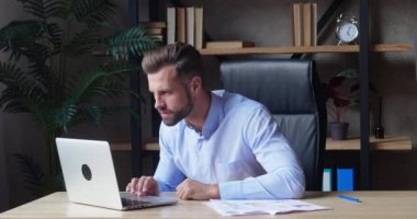 Mavi tişörtlü bir işadamı dizüstü bilgisayara dikkatle bakar ve bir rahatsızlık duygusu ifade eder. Şirket ya yenilir ya da anlaşma başarısız olur.