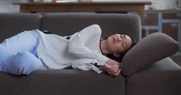 Апатичная или скучающая молодая азиатская сонная женщина падает на диван. Уставшая ленивая леди спит дома одна на диване. Забавная девушка спит, чувствуя отсутствие мотивации, усталости или депрессии — стоковое видео