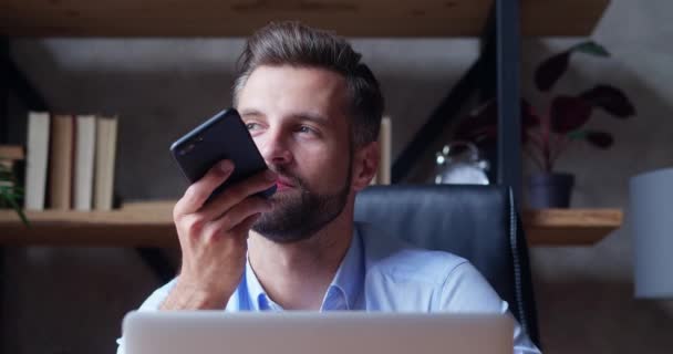 Un hombre de negocios sostiene un teléfono inteligente en sus manos y graba un mensaje de voz — Vídeos de Stock