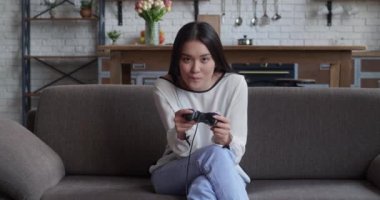 Koltukta oturan ve dijital konsolda video oyunlarında oynayan güzel Asyalı oyuncu kızın portresi. Cesur Oyuncu Kadın Video Oyunu için Joystick 'i kontrol ediyor. Oyun Odaklı Bir Kişi