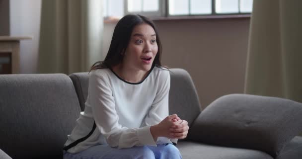 Emocionado chica asiática viendo la televisión en casa. Lotto ganadora, alegre mujer celebrando el concepto. — Vídeos de Stock