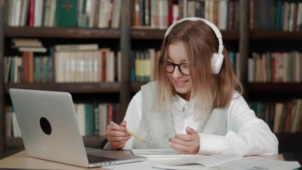Genç kızlar okulunda kulaklık takıyor. İnternette web sayfası yazıları okuyup dizüstü bilgisayarlara bakarak uzak mesafe kurslarına ya da webcam 'den video öğretmenlerine bakarak öğreniyorlar.. — Stok video