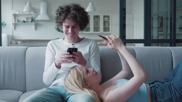 Attraktive Paar auf der Couch mit Gadgets im Chat und Messaging. Eifersucht, Internet-Liebhaber, Online-Schummelei — Stockvideo