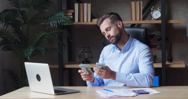 Young male entrepreneur counting money at his desk — Stock Video