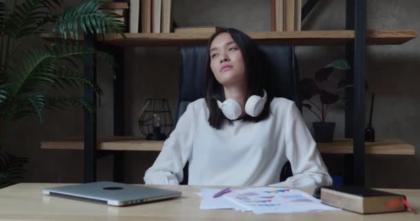 Asian woman leaning on the back of an armchair after a hard working day and looking away — Stock Video