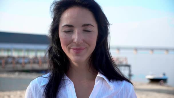 Ritratto di bella giovane donna bruna sorridente allegro godendo stile di vita guardando la fotocamera sulla calma spiaggia tramonto bellezza femminile — Video Stock