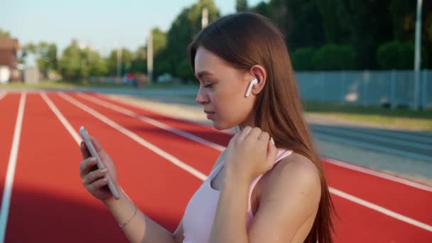 跑步妇女与健美跟踪和运行应用程序可穿戴技术与智能手机和耳机。健康的生活方式. — 图库视频影像