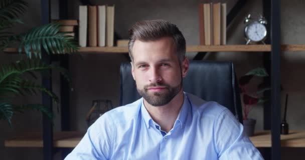 Lachende bebaarde duizendjarige professionele zakenman die naar de camera kijkt. Gelukkige zelfverzekerde knappe jonge volwassen ondernemer, leider, manager poseren in het kantoor. close-up gezicht uitzicht bedrijf portret — Stockvideo