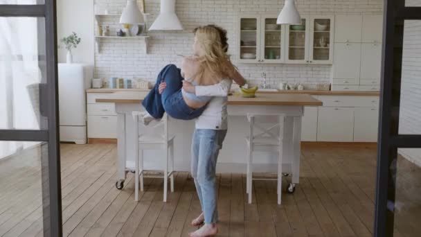 Happy couple spinning around in new house. Young couple celebrating relocation together. Smiling man and woman having fun at luxury house. Love couple hugging in new apartment — Stock Video