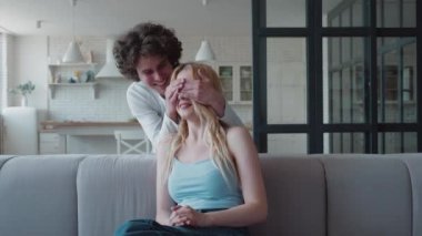 Genç çift yeni bir daireye taşınıyor. Sarışın kadınların yüz ifadelerini yakından çek. Adam arkada durur ve yüzünü ellerle kapatır..