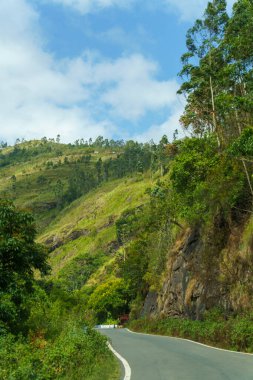 Arka planda yamaç olan bir yol. Yol boş ve gökyüzü temiz.