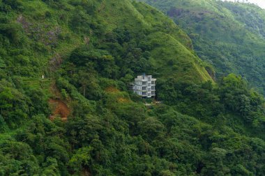 Tepesinde bir ev olan bir dağ. Ev beyaz ve bir sürü penceresi var.
