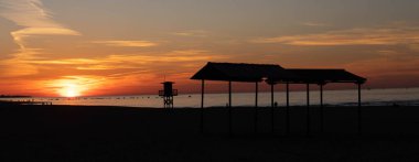 Playa al anochecer con el sol de fondo
