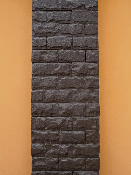 Pólo de pedra marrom escuro e parede laranja — Fotografia de Stock